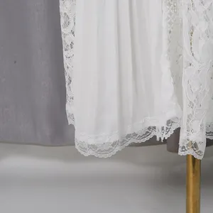 Close-up detail of white hollow lace hem and delicate pleated chiffon texture