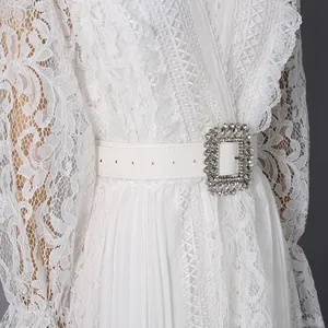 Detailed shot of white lace dress waist featuring elegant crystal-encrusted belt buckle