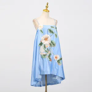 Detail van een lichtblauwe satijnen slipdress met prachtig groot bloemenborduurwerk