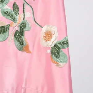 Detailopname van het bloemenborduurwerk op een roze satijnen retro vintage jurk.