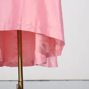 Gedetailleerde close-up van de roze satijnen jurkzoom met stiksels en binnenvoering