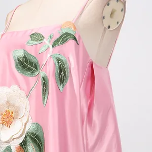 Gedetailleerd overzicht van een roze satijnen jurk met fijn bloemenborduursel en bladeren