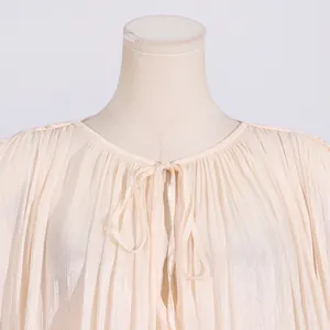 Detailed view of sweet style light apricot pleated dress featuring a round neck and front tie