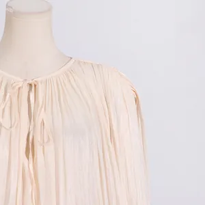 Close-up detail of elegant pleated dress with round neck and front tie-up design