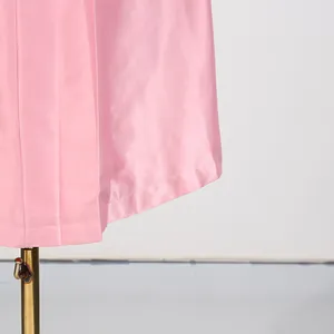 Detailopname van de zoom van een roze satijnen plooijurk met fijne textuur en naden