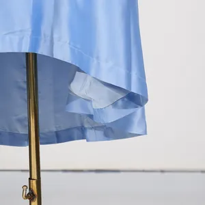 Detailopname van de zoom van een lichtblauwe satijnen jurk met zijden textuur.