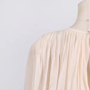 Macro detail of elegant pleated champagne dress showing fine shimmering fabric texture