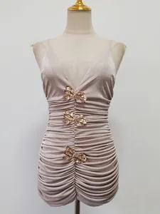 Elegante abito aderente arricciato color champagne con fiocchi in metallo dorato da sera.