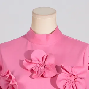 Detailed view of exquisite 3D floral appliqués on a bright pink standing collar dress