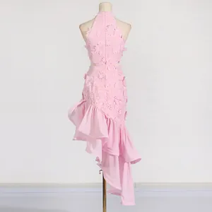 Back view of pink lace holiday dress featuring cutout waist and asymmetrical ruffles