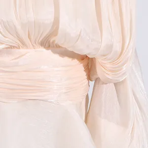 Close-up of elegant champagne pleated fabric and waist detail on a summer dress.