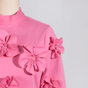Detail of pink mock neck dress featuring elaborate 3D floral appliqué on shoulder and sleeve