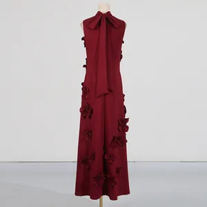 Detail of burgundy sleeveless dress featuring 3D floral appliqués and a back bow tie.