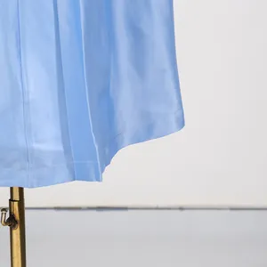Detail van de zoom van de lichtblauwe jurk met gladde stoftextuur en fijne stiksels