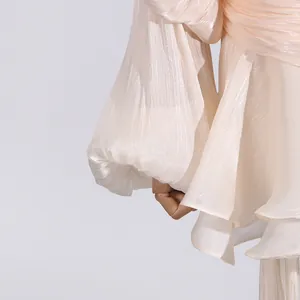 Detailed macro view of the pleated fabric texture and ruffled sleeves on this apricot dress.