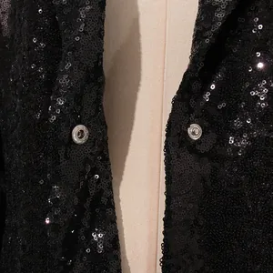 Detalle de chaqueta tipo blazer con lentejuelas negras y cierre de botón a presión metálico