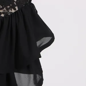 Detailed view of black lace embroidery and layered chiffon ruffles on resort dress.