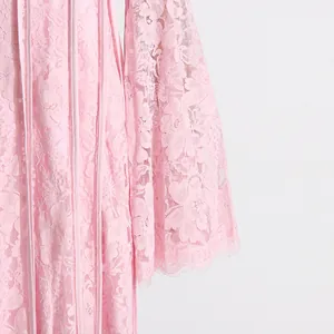 Close-up of pink French lace dress showing intricate floral embroidery and bell sleeves