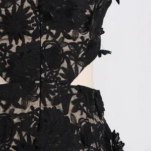 Close-up of black floral lace fabric with elegant waist cut-out detail on a dress