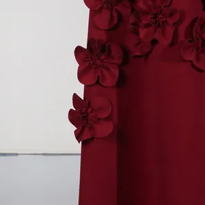 Close-up detail of handcrafted 3D flower appliques on burgundy red dress fabric.