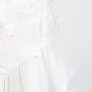 Close-up of white floral lace embroidery and ruffled skirt texture on a holiday dress