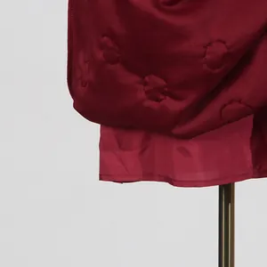 Close-up of burgundy dress hem showing unique quilted circular pattern and satin finish