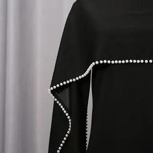 Detaillierte Nahaufnahme eleganter Perlenverzierungen an einem schwarzen Vintage-Schalkleid