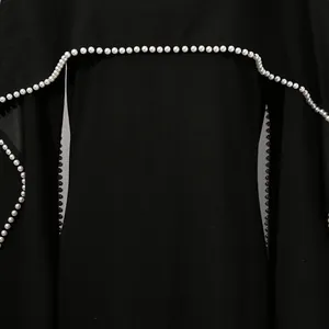 Detailansicht eines eleganten schwarzen Vintage-Kleides mit aufwendigem Perlenbesatz am Umhang.