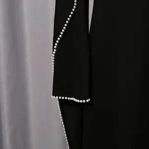 Detailaufnahme eines eleganten schwarzen Kleides mit edlen Perlenstickereien an den Rändern