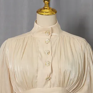 Detailed view of elegant vintage champagne dress featuring a high collar and pearl floral buttons