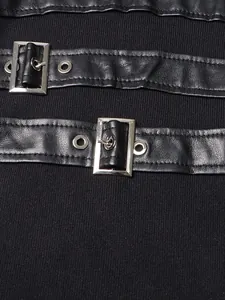Gros plan sur les boucles en métal argenté et les lanières en similicuir d'une robe en maille noire.