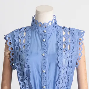 Détails d'une robe bleue avec broderies délicates, dentelle ajourée et boutons en perles