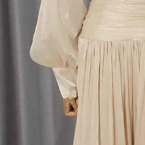 Detail view of elegant pleated champagne dress with shimmering fabric and puff sleeves.