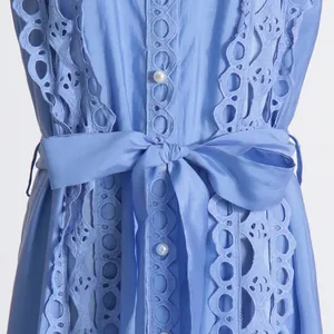 Détail d'une robe bleue de style français avec broderie ajourée et boutons en perles