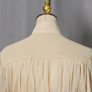 Close-up of the pleated yoke and shimmering champagne fabric of an elegant dress