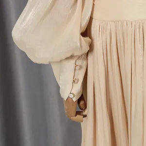 Close-up of elegant champagne dress featuring lantern sleeves and delicate row buttons