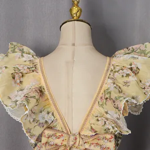 Detailed view of backless yellow floral dress featuring delicate ruffles and bow tie detail