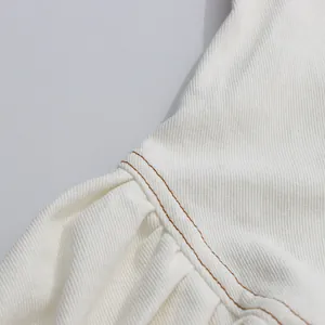 Detailansicht der hochwertigen braunen Doppelnaht an einem weißen ärmellosen Kleid aus Twill