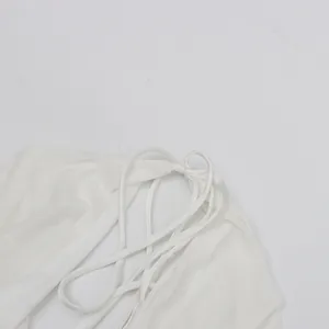 Détail d'une robe dos nu en satin blanc montrant les bretelles élégantes et la texture du tissu