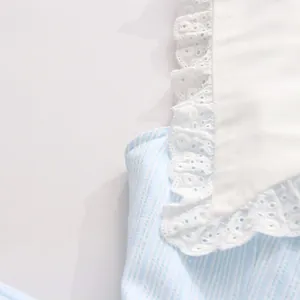 Nahaufnahme der filigranen weißen Spitzbordüre an einem blau-weiß gestreiften Kleid