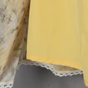 Detail shot of a yellow sweet style dress featuring floral mesh and white lace trim.
