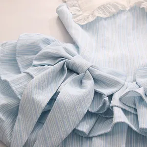 Nahaufnahme eines blau gestreiften Kleides mit großer Schleife und weißer Spitzenstickerei