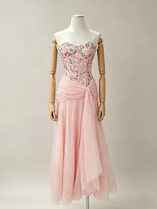 Elegant French floral corset maxi dress with flowing pink chiffon skirt on wooden mannequin