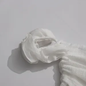 Macro detail of white flowy fabric with ruffle design on asymmetric halter dress