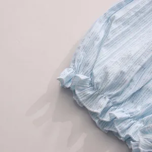Nahaufnahme des zarten blau gestreiften Rüschensaums an einem süßen Sommerkleid für Damen
