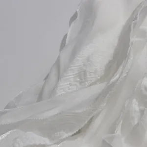 Close-up of white sheer fabric with intricate textures and ruffled details of the dress