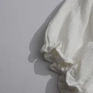 Detailed macro view showing the white ruffled sleeve and textured fabric on a flowy dress