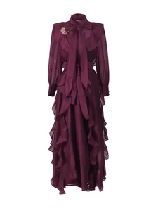 Elegant plum purple ruffled maxi dress with bow tie neck and gold flower brooch accessory.