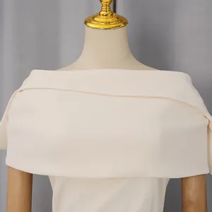 Dettaglio di un elegante abito a scialle color crema con spalle scoperte su un manichino.