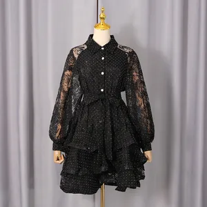 Elegant black polka dot dress with lace sleeves and ruffled skirt on a mannequin